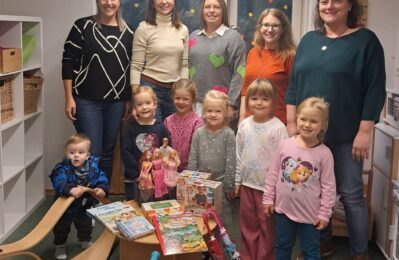 Gruppe von Erwachsenen und Kindern, davor Spielzeug